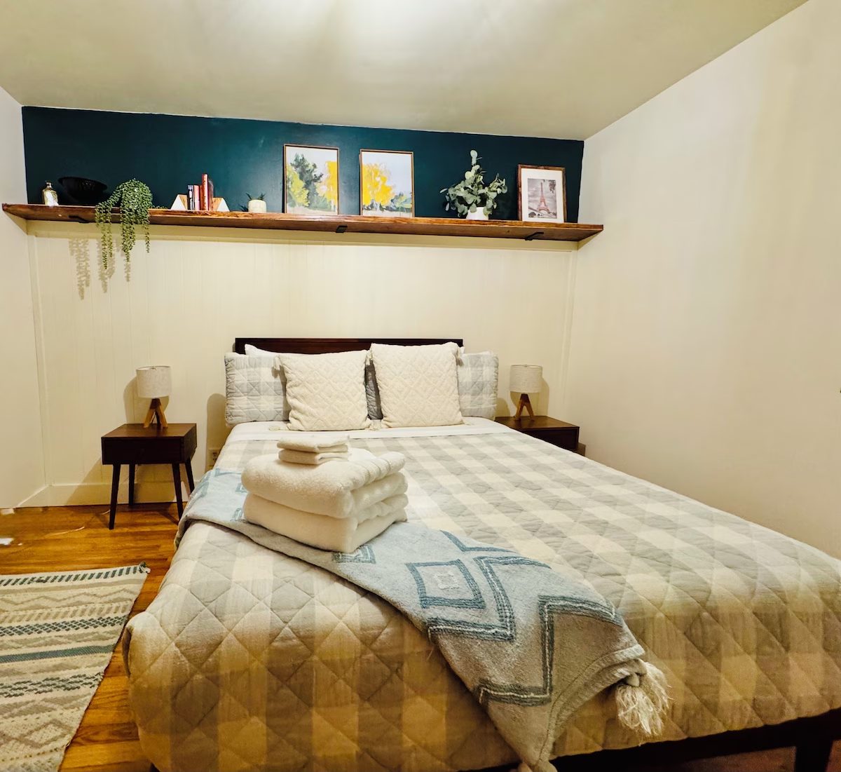 Bedroom with a teal accent wall, picture shelf and quilted bedding