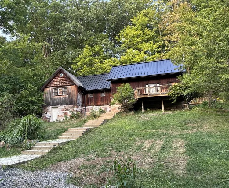 The cabin from the yard in summer, stone steps leading up to the deck