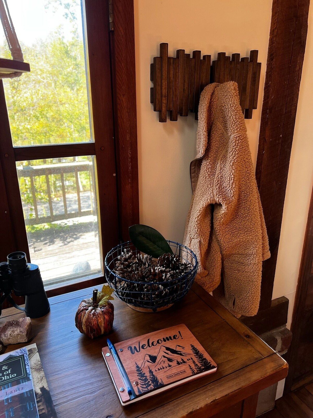 The entry table with the guest book, binoculars and a basket of pine cones by the window