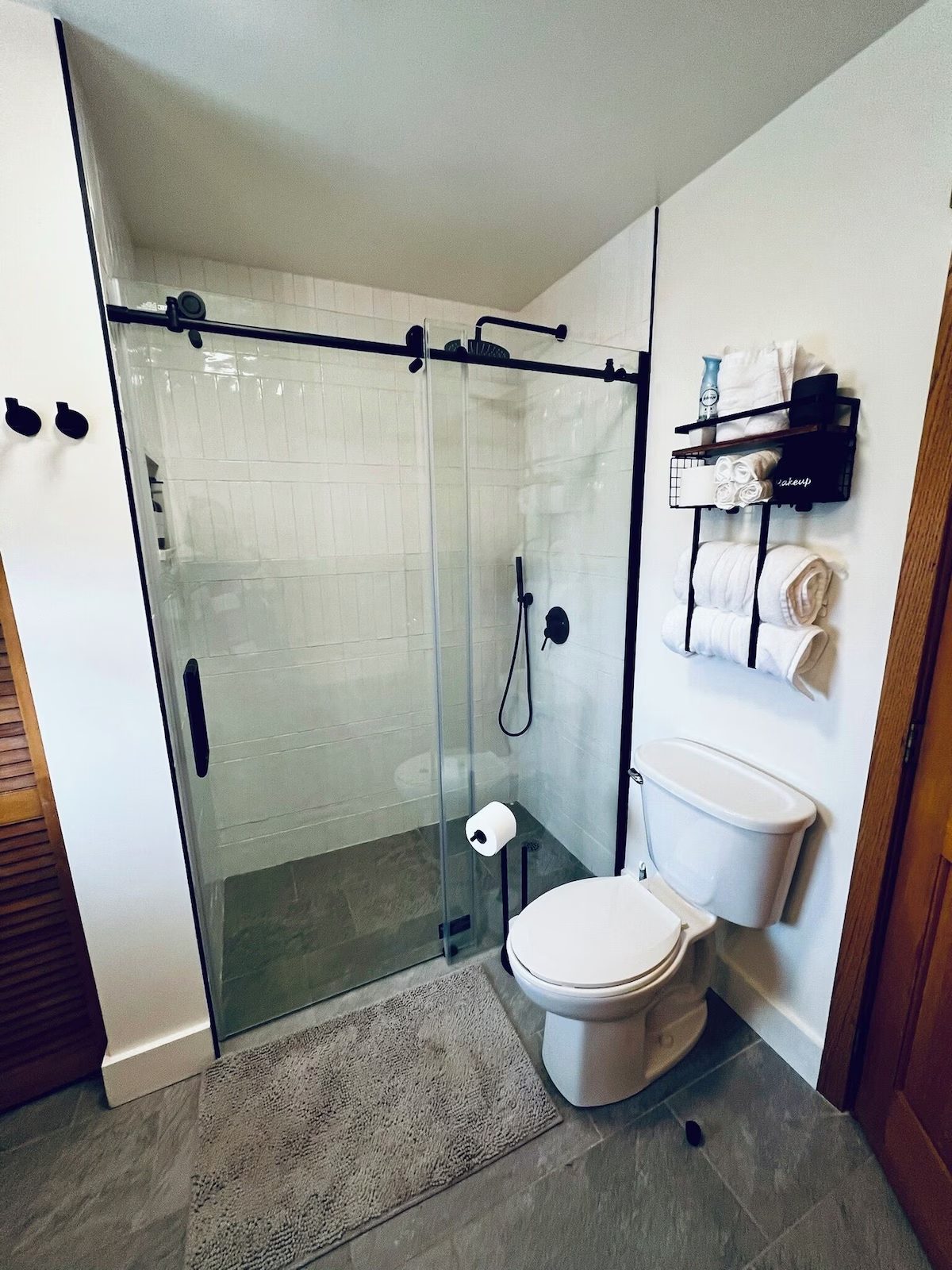 The guest bath with a glass-enclosed shower, white tile and rolled towels