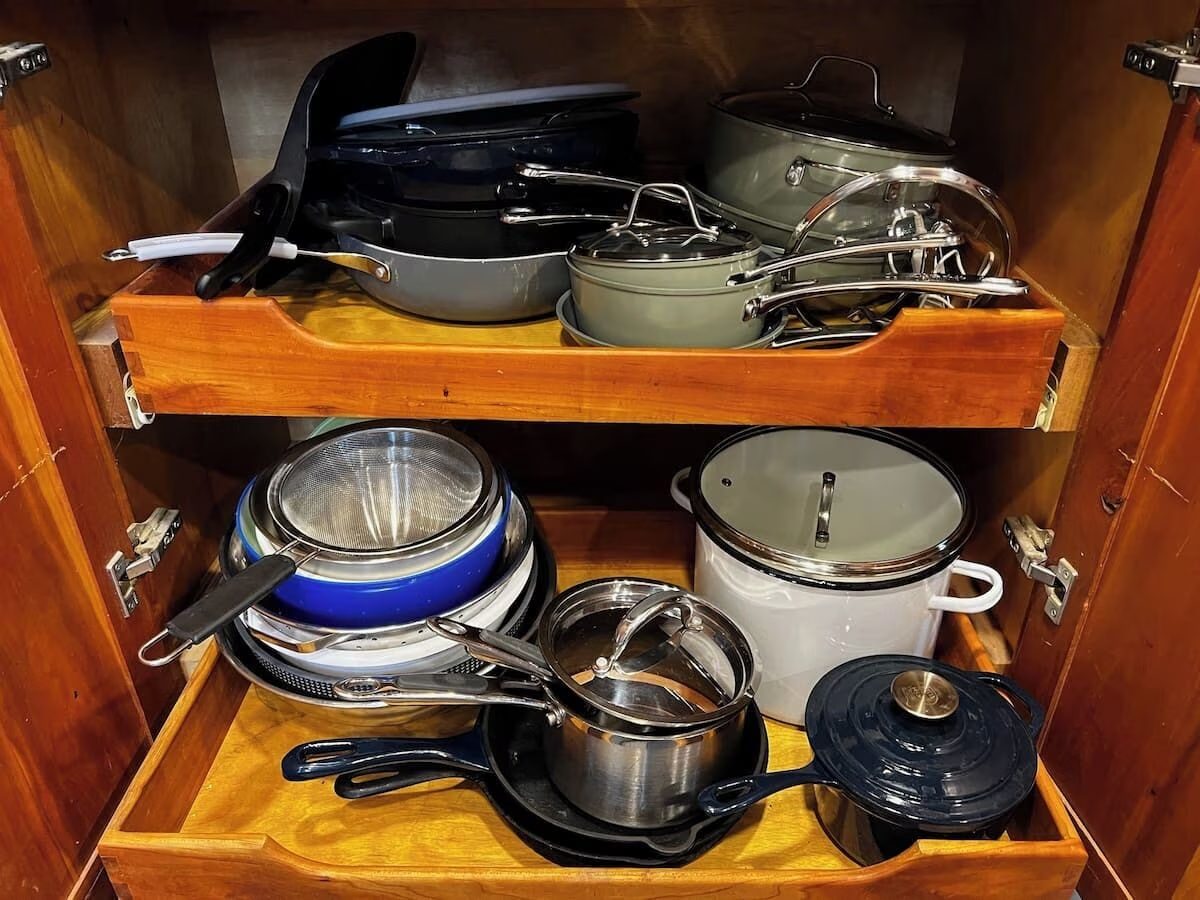 Open cabinet with pots, pans and a stock pot on pull-out shelves