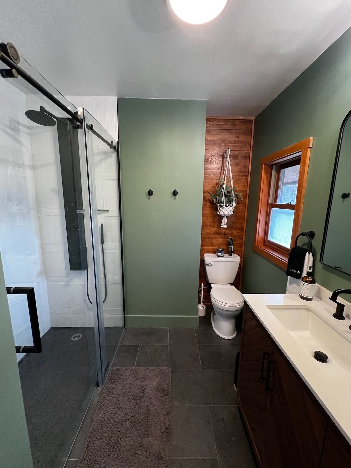 The master bath with a glass shower, green walls and a wooden accent wall