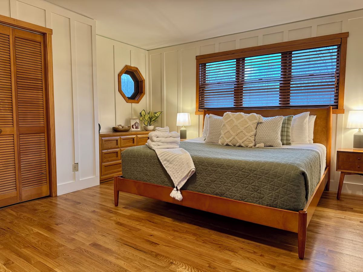 The master bedroom with a king bed, wood floors and panelled walls